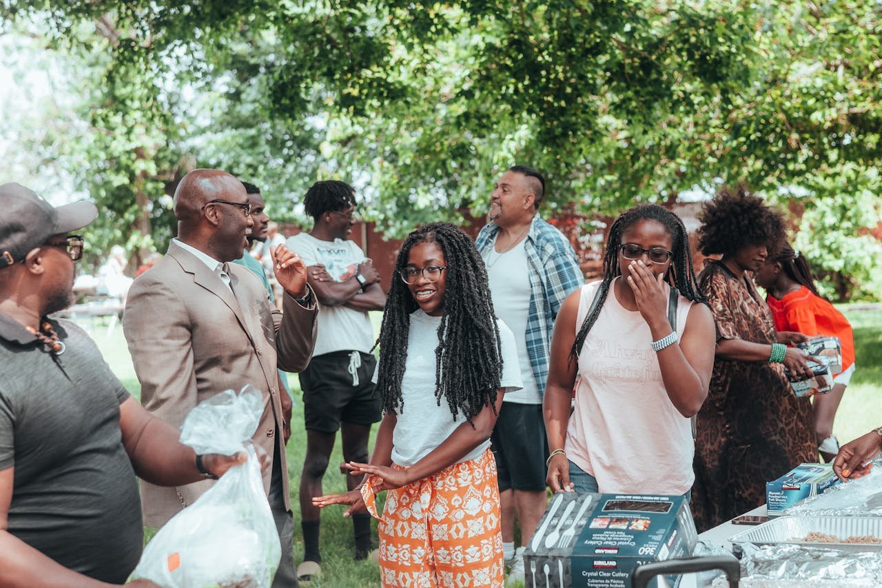 A diverse group of people engaging in conversation and laughter during an outdoor social event.