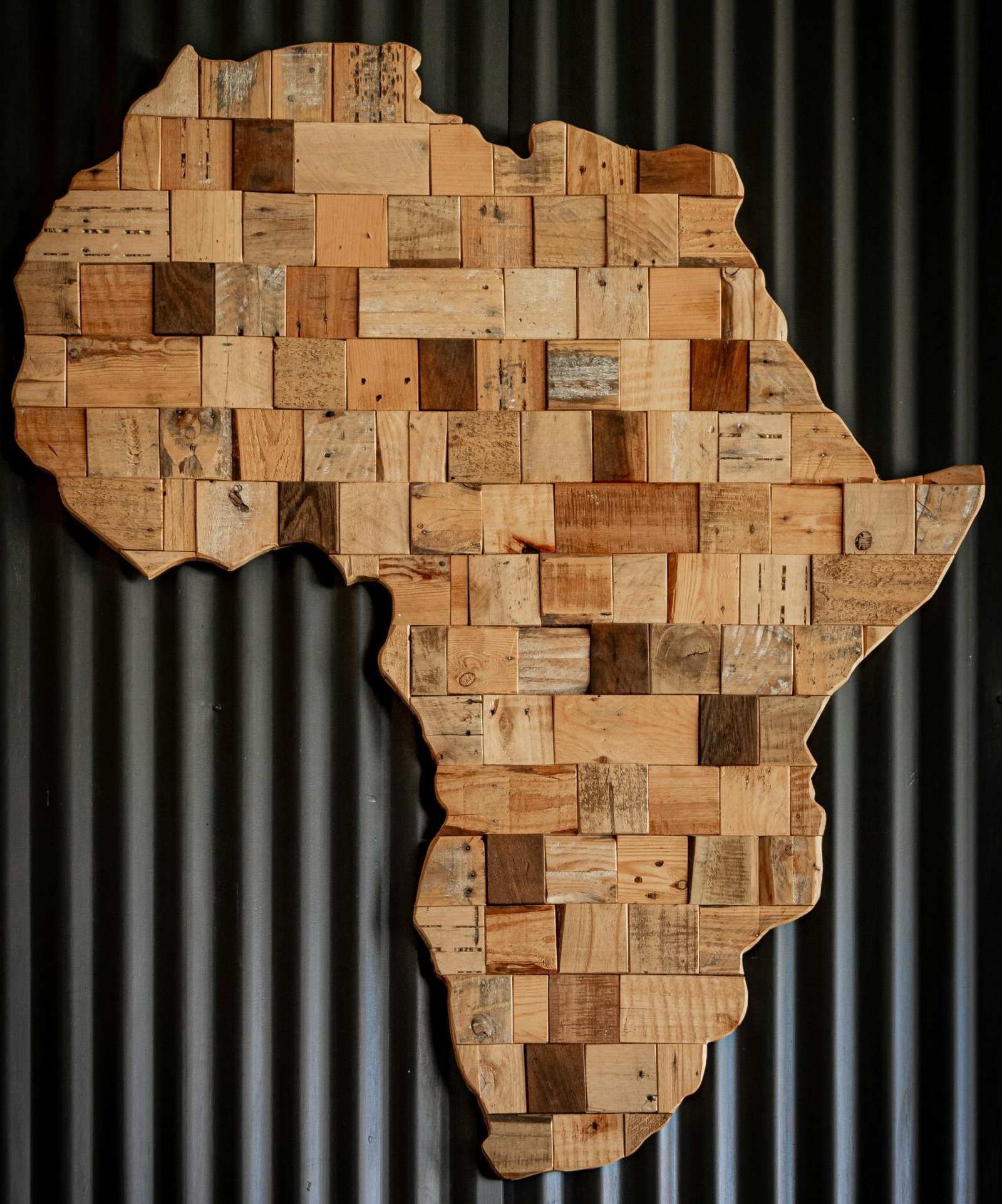 Artistic wooden map of Africa against dark corrugated background.