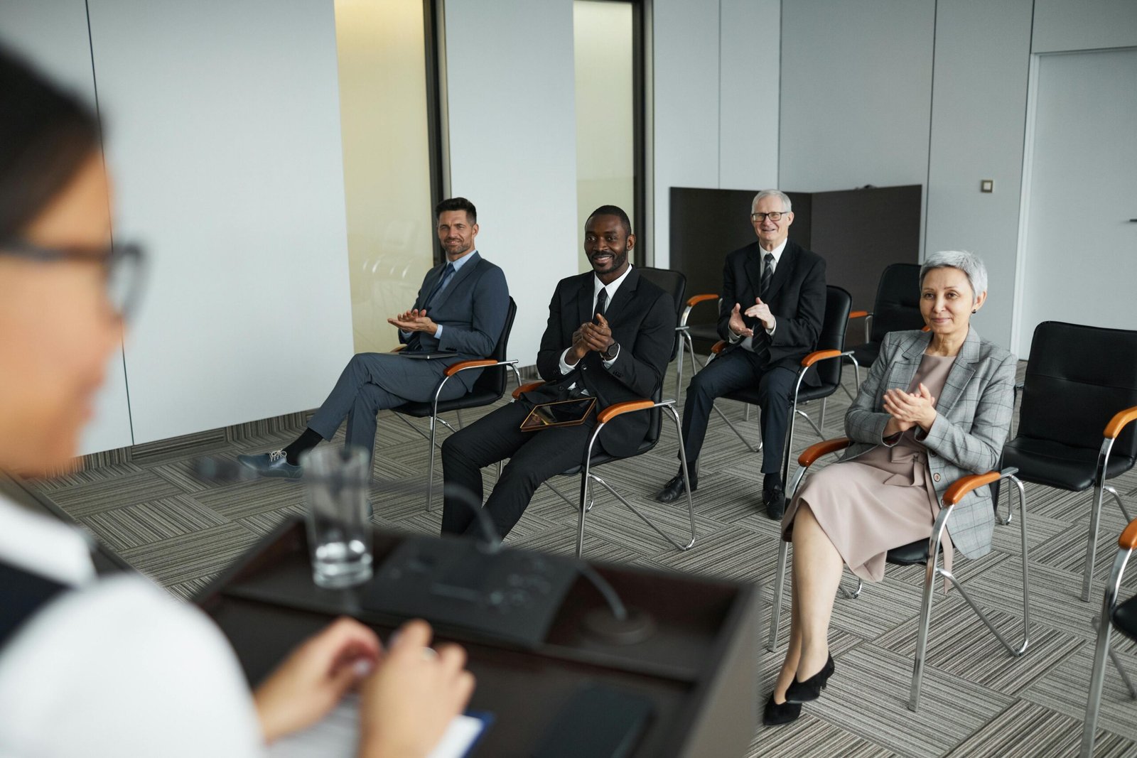 A diverse group of business people clapping in a conference room setting.